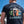 Man wearing a blue harvey's t-shirt with 'The Best of Sussex' graphic design outdoors.