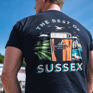 Man wearing a blue harvey's t-shirt with 'The Best of Sussex' graphic design outdoors.